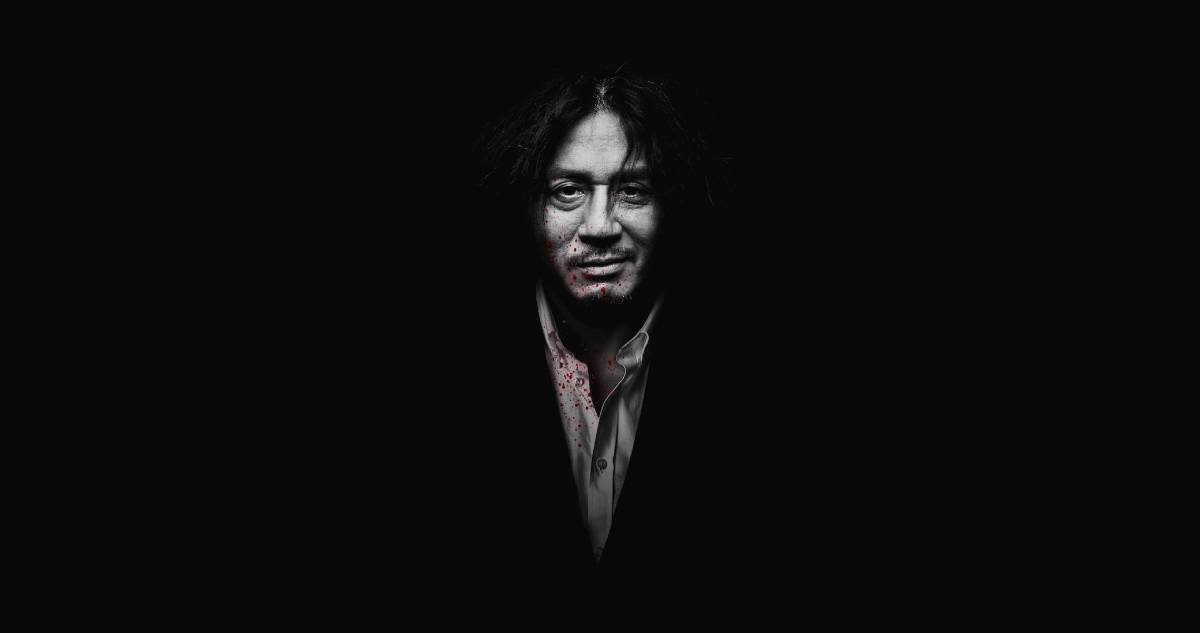 A dark figure in a blood-stained shirt stands against a black background, creating a mysterious and unsettling atmosphere. Poster of film - Oldboy (2003)