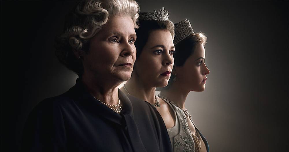Three elegantly dressed women stand in profile, each adorned with crowns, illuminated against a dark backdrop, exuding regal grace.