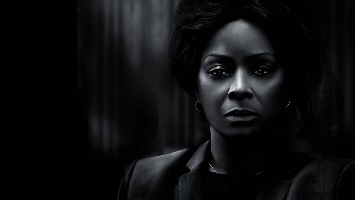 A stylized portrait of a person wearing a dark suit, captured in dramatic shadows and soft lighting for a mysterious effect.